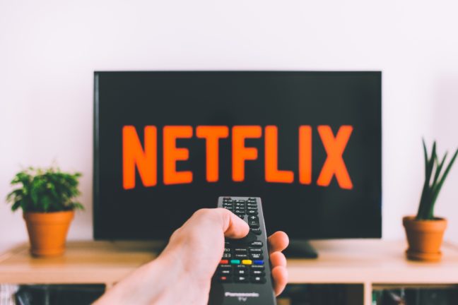 netflix on tv person holding remote
